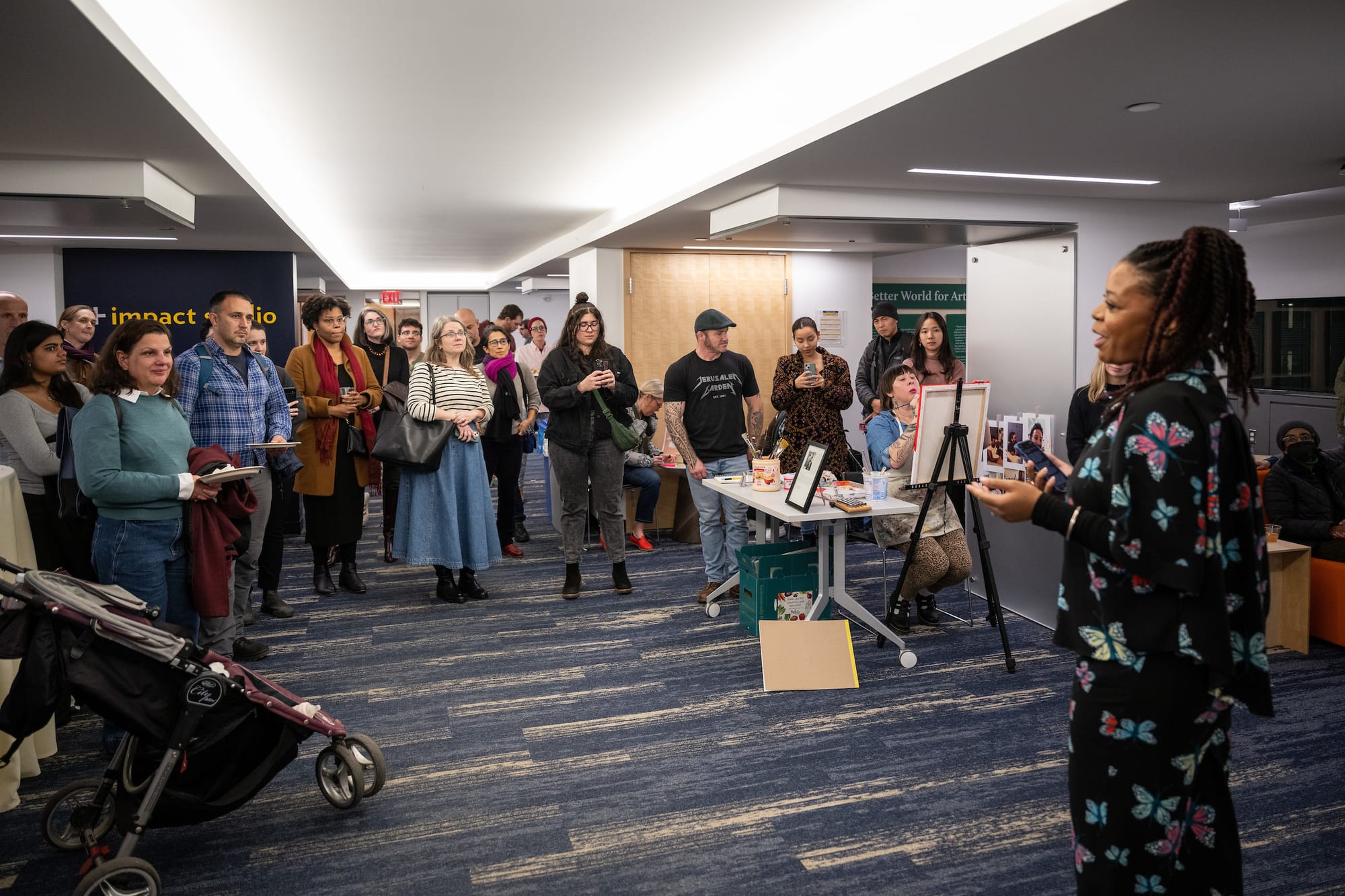 A photo of me, dressed in a butterfly two piece outfit addressing a small crowd of people in the installation